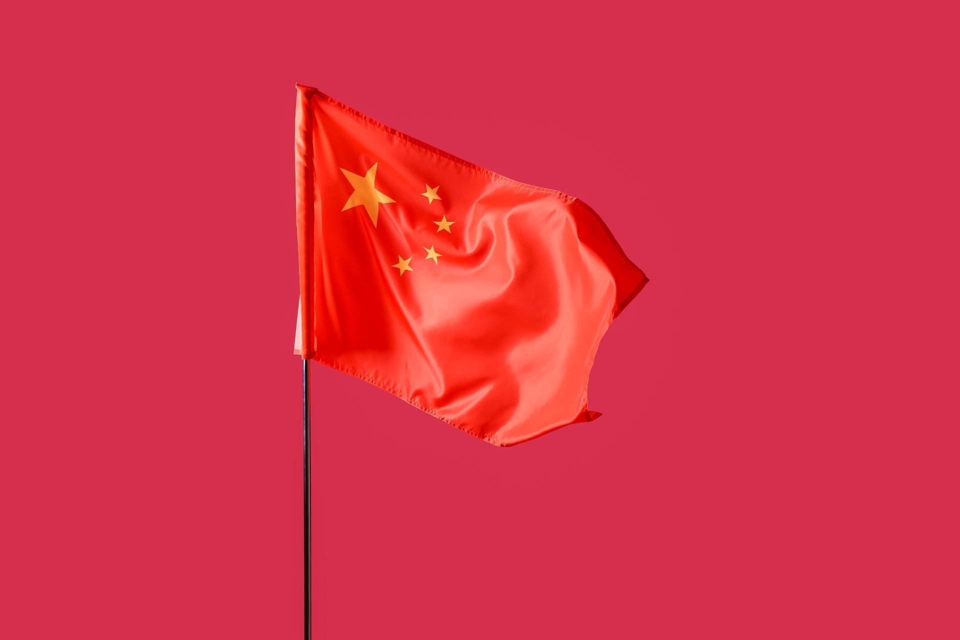 A vibrant red flag of China featuring a large golden star and four smaller stars, symbolizing the unity of the country.