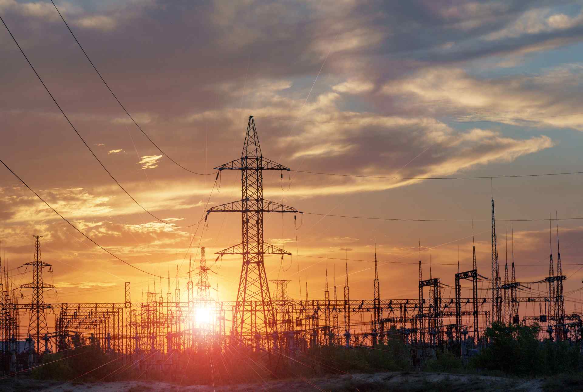 "Power grid at sunset with transmission towers and lines."