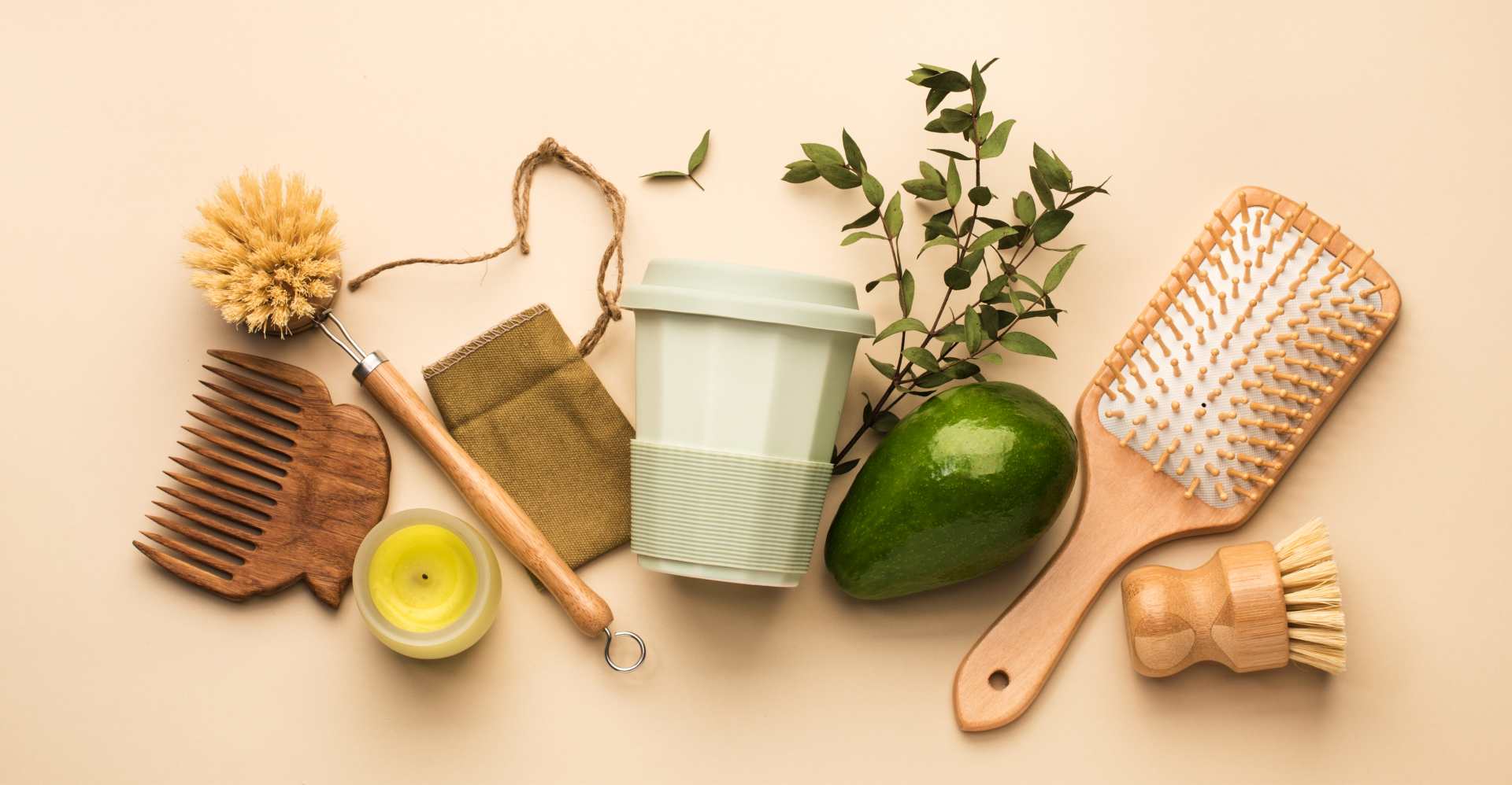A collection of eco-friendly personal care items, including a wooden comb, bamboo brushes, a reusable cup, and natural leaves, promoting sustainable living.