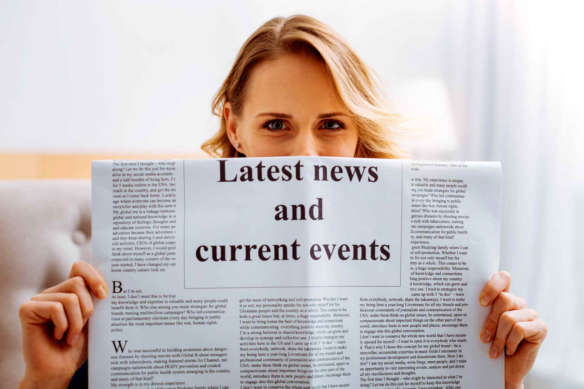 A woman holding a newspaper titled "Latest News and Current Events," symbolizing staying informed.