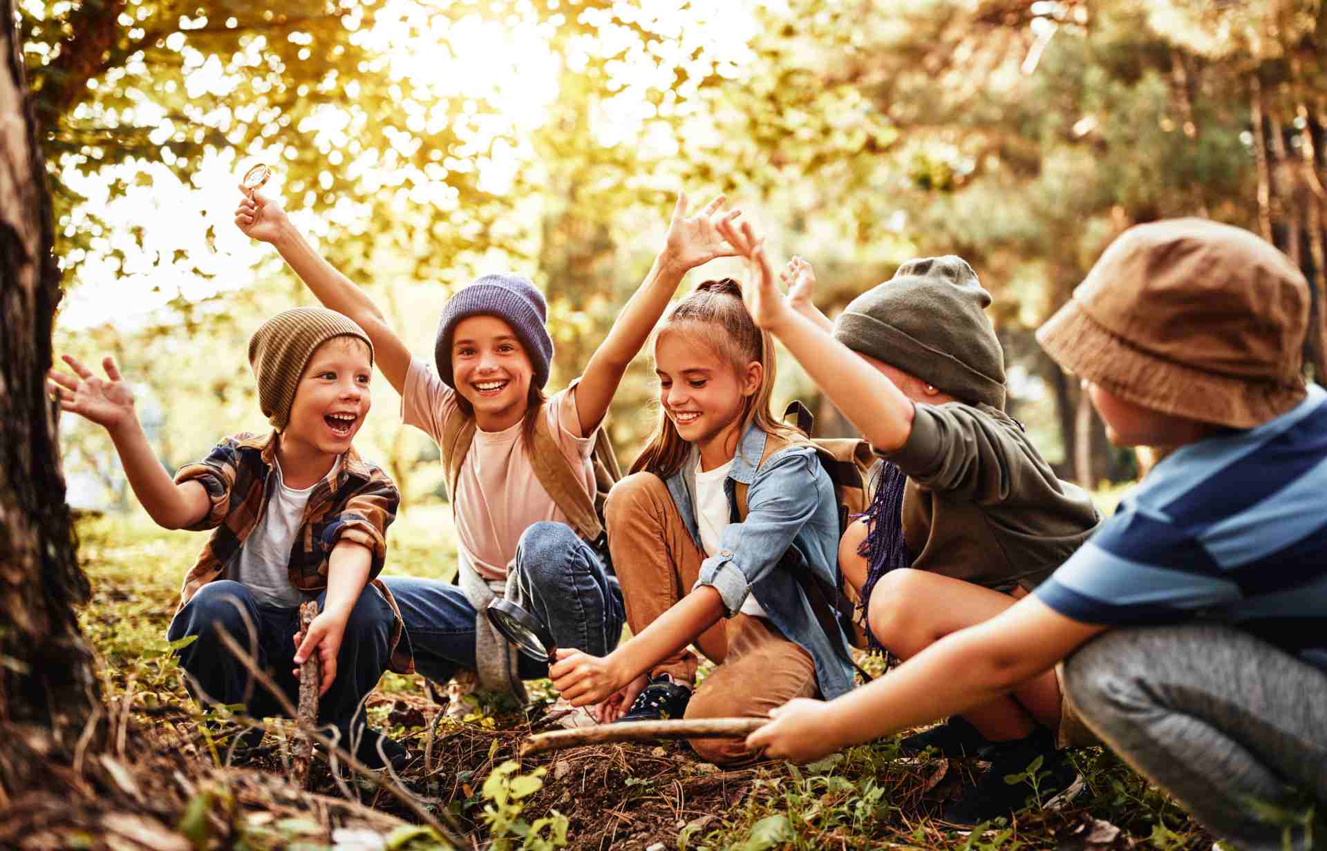 Kids exploring the forest with sticks and a magnifying glass, learning survival skills.