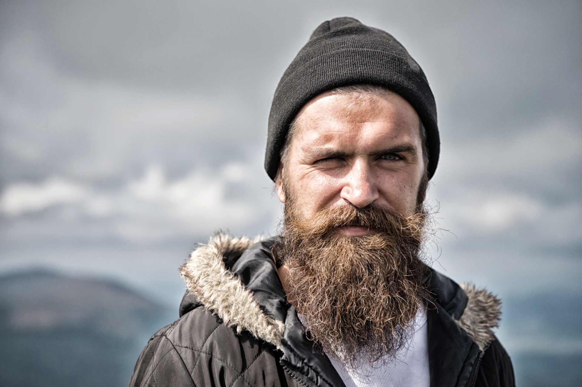 A rugged individual wearing a beanie and fur-lined jacket, representing the persona of a survivalist prepared for harsh environments.